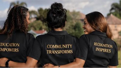 Three women wearing EmpowerAfriq shirts: education empowers, community transforms, recognition inspires